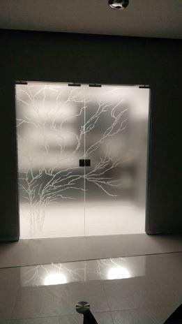 Porta in vetro 8mm extrachiaro arricchito dalla rappresentazione di un albero, lavorato in sabbiatura, che abbraccia entrambe le ante