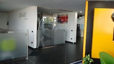 Parete divisoria fissa con apertura scorrevole in vetro temperato trasparente arricchita da lavorazione di sabbiatura.