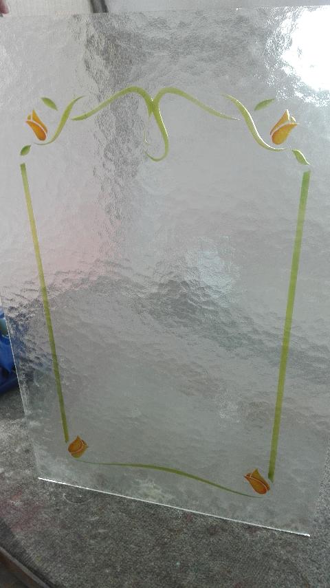 Vetro 4mm cattedrale bianco arricchito da un semplice decoro, scavato e colorato, che va a creare una cornice interna, arricchita da dei piccoli tulipani nei quattro angoli.