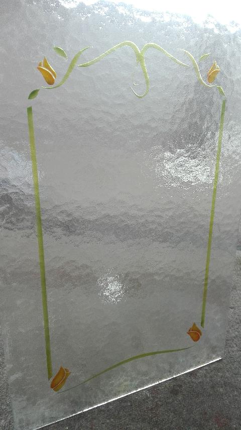 Vetro 4mm cattedrale bianco arricchito da un semplice decoro, scavato e colorato, che va a creare una cornice interna, arricchita da dei piccoli tulipani nei quattro angoli.