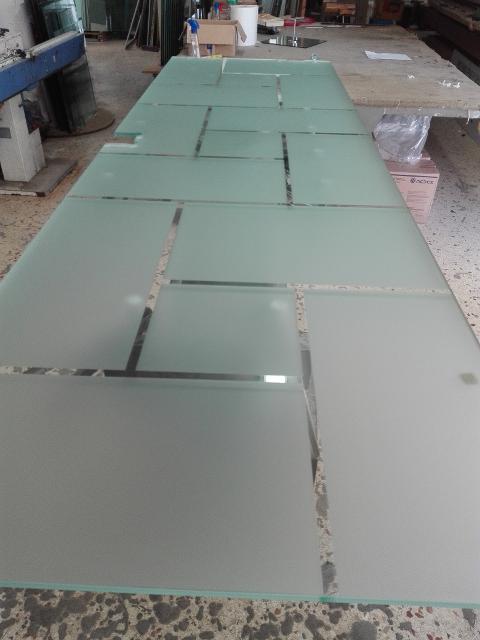 Anta di porta in vetro temperato 8mm trasparente decori rettangolari, disposti in varie angolazioni, lavorati in sabbiatura, lasciando uno spazio fra le figure geomentriche di 1cm in trasparenza. In seguito è stato applicato su tutta la superficie un prodotto acidante per rendere satinata la parte in sabbiatura.