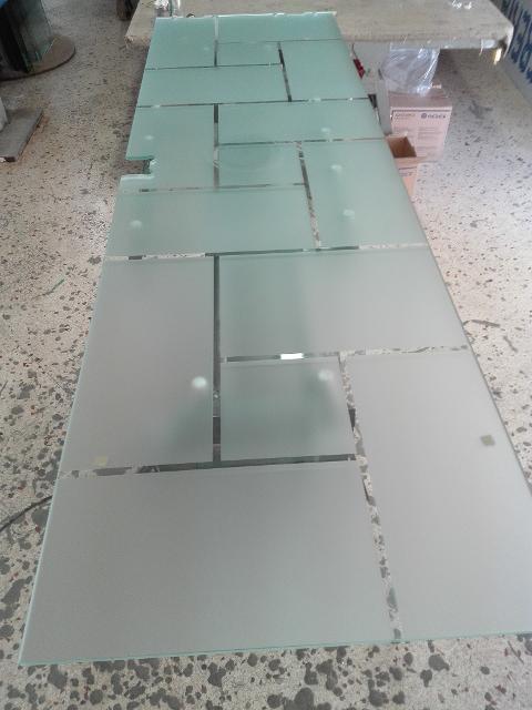 Anta di porta in vetro temperato 8mm trasparente decori rettangolari, disposti in varie angolazioni, lavorati in sabbiatura, lasciando uno spazio fra le figure geomentriche di 1cm in trasparenza. In seguito è stato applicato su tutta la superficie un prodotto acidante per rendere satinata la parte in sabbiatura.