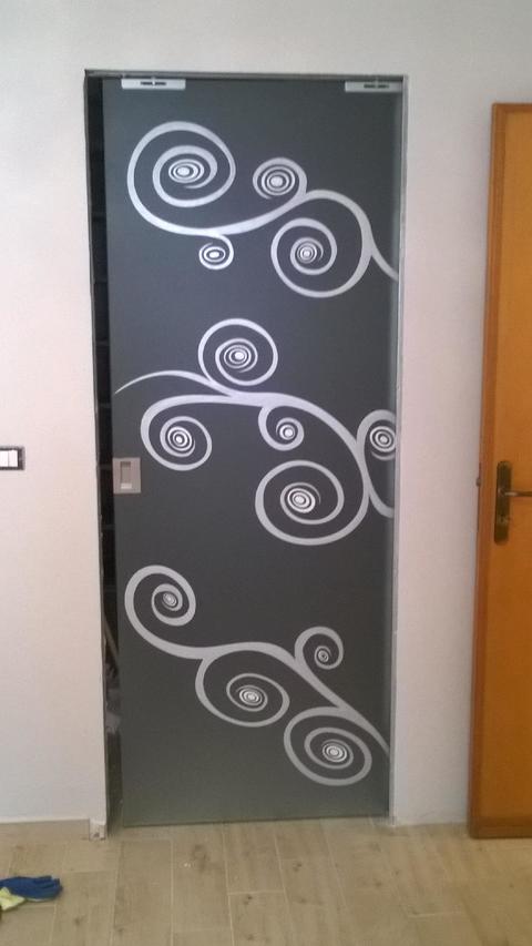Porta scorrevole in vetro temperato satinato con decori scavati e verniciati in argento con paticolari in bianco.