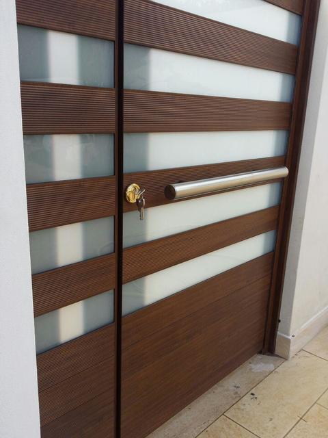 Cancello in alluminio anodizzato con 2 ante effetto legno e inserti in vetro. Maniglione in alluminio anodizzato effetto inox.